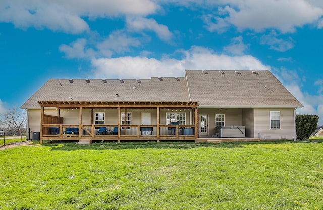 back of house featuring central AC, a wooden deck, a lawn, and a hot tub