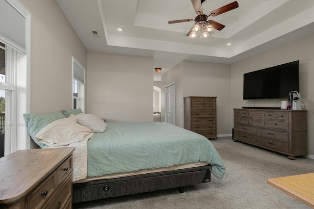 bedroom with light carpet, a tray ceiling, baseboards, and a ceiling fan