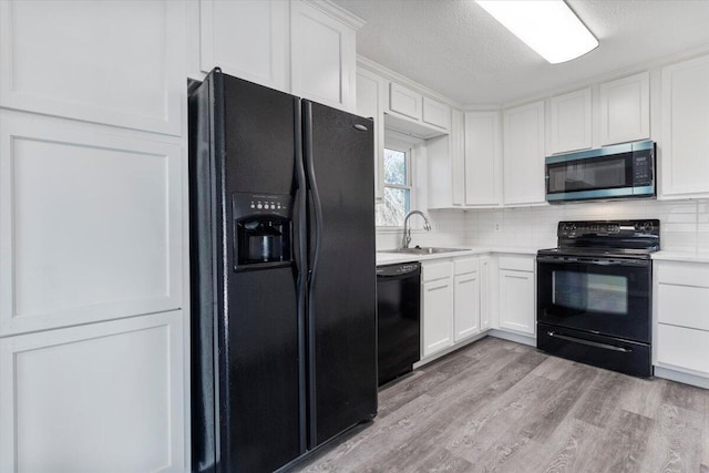 1945 Debra Dr, West Plains, MO 65775 - kitchen with white cabinets, a sink, light countertops, black appliances, and decorative backsplash