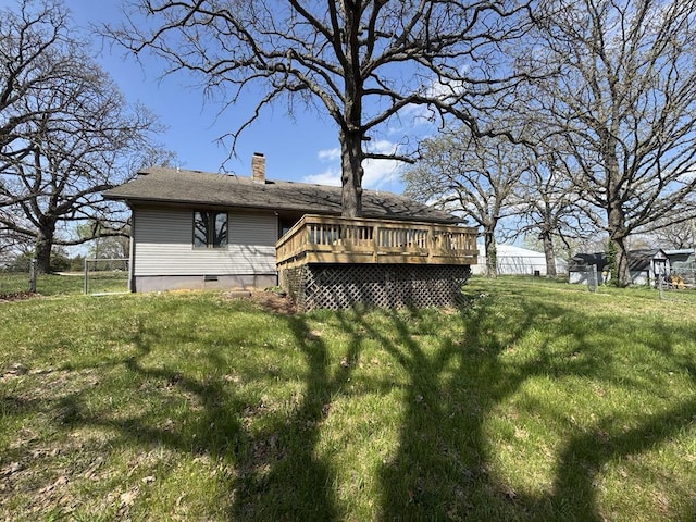 back of property featuring fence, a deck, crawl space, a chimney, and a yard