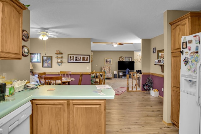 kitchen featuring light wood-type flooring, a ceiling fan, a peninsula, and white appliances