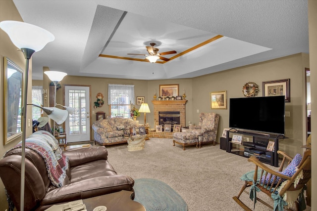 carpeted living area featuring a raised ceiling, ceiling fan, and a fireplace