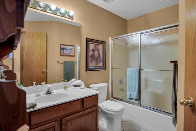 full bathroom featuring tile patterned flooring, vanity, toilet, bath / shower combo with glass door, and a textured ceiling