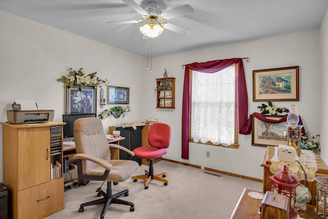 office space featuring visible vents, baseboards, light colored carpet, a textured ceiling, and a ceiling fan