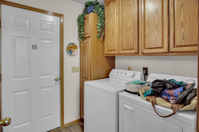 washroom with cabinet space, wood finished floors, and washing machine and clothes dryer