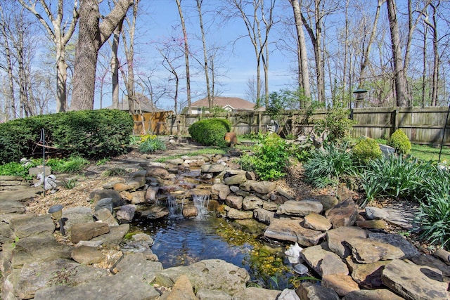 view of yard with a fenced backyard and a garden pond