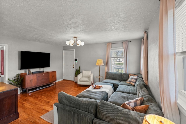 living room featuring a notable chandelier, wood finished floors, and a textured ceiling