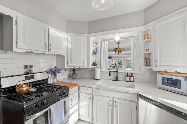 kitchen with light countertops, a sink, open shelves, and appliances with stainless steel finishes