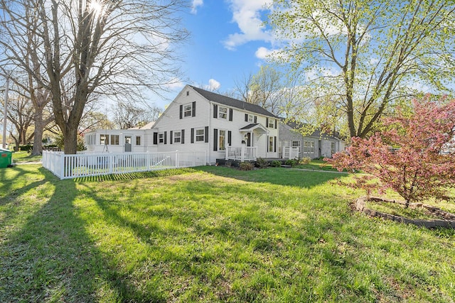 rear view of house featuring fence and a lawn