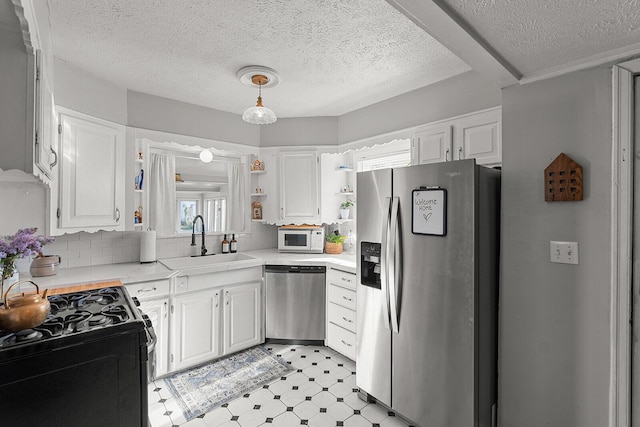 kitchen featuring light countertops, open shelves, light floors, stainless steel appliances, and a sink