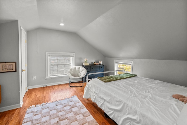 bedroom with baseboards, vaulted ceiling, and wood finished floors
