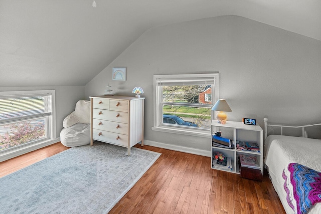 bedroom featuring baseboards, multiple windows, vaulted ceiling, and hardwood / wood-style flooring
