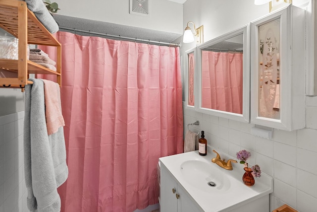 bathroom featuring vanity, visible vents, a shower with shower curtain, tile walls, and backsplash