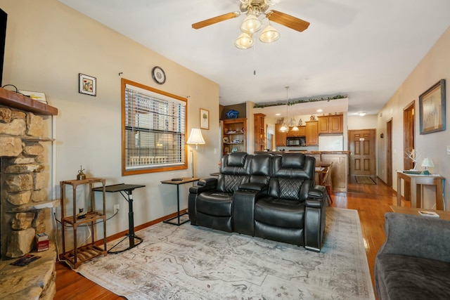 living area with light wood-style flooring, baseboards, and ceiling fan