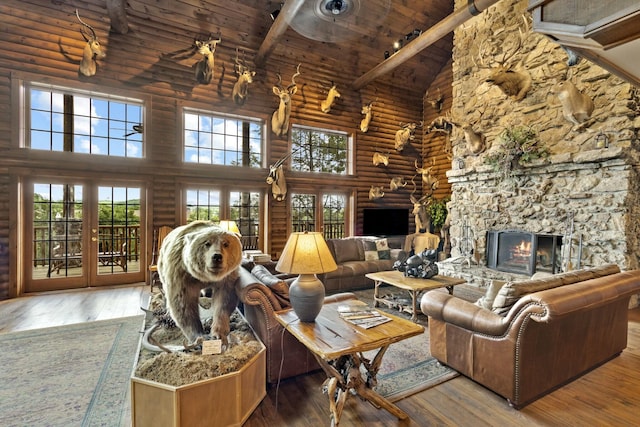 living area featuring a stone fireplace, rustic walls, wood ceiling, beamed ceiling, and hardwood / wood-style floors