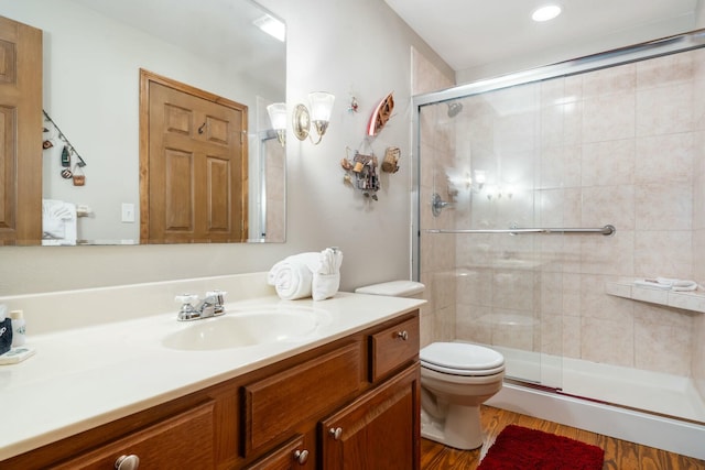 bathroom featuring toilet, a stall shower, wood finished floors, and vanity