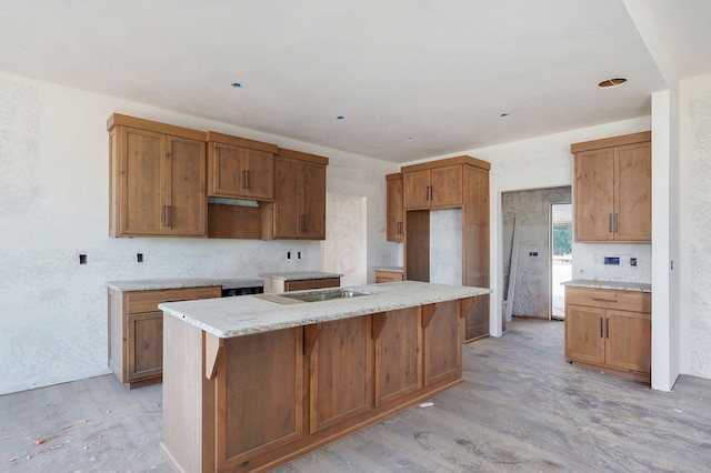 LOT69 W Marty St, Springfield, MO 65810 - kitchen featuring light wood-style floors, an island with sink, brown cabinetry, light stone counters, and a breakfast bar area