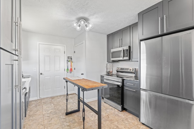 715 Woodlawn St, Marshfield, MO 65706 - kitchen with baseboards, appliances with stainless steel finishes, gray cabinetry, and a textured ceiling