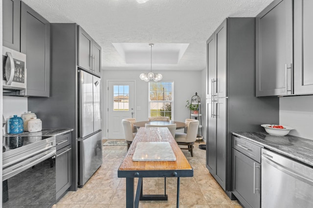 715 Woodlawn St, Marshfield, MO 65706 - kitchen featuring a raised ceiling, an inviting chandelier, appliances with stainless steel finishes, a textured ceiling, and gray cabinetry