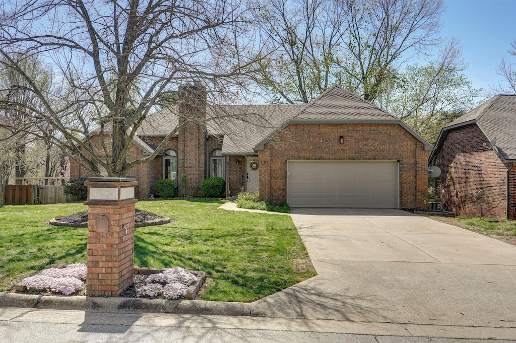 view of front facade featuring a garage, a chimney, concrete driveway, brick siding, and a front lawn