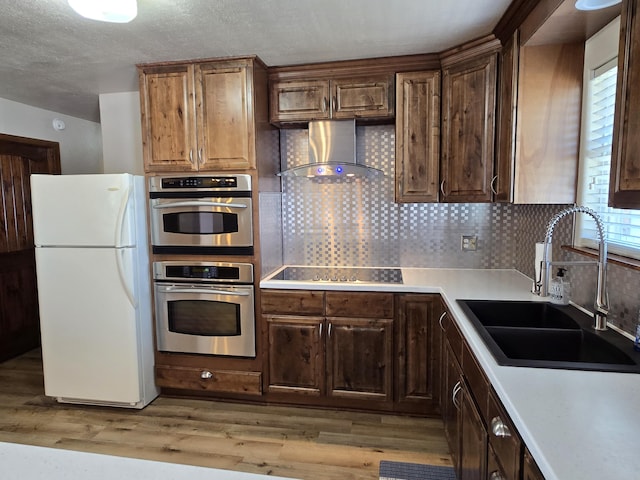 21282 County Road 295, Hermitage, MO 65668 - kitchen with wall chimney range hood, a sink, a wealth of natural light, black electric stovetop, and freestanding refrigerator