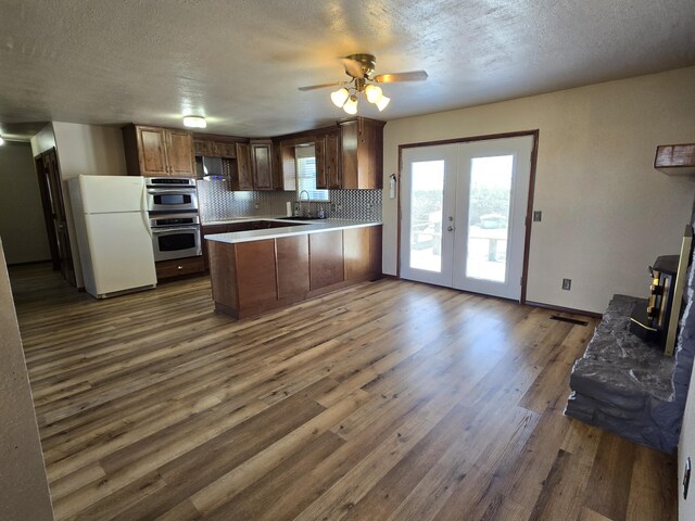 21282 County Road 295, Hermitage, MO 65668 - kitchen with dark wood finished floors, a wood stove, freestanding refrigerator, a peninsula, and tasteful backsplash