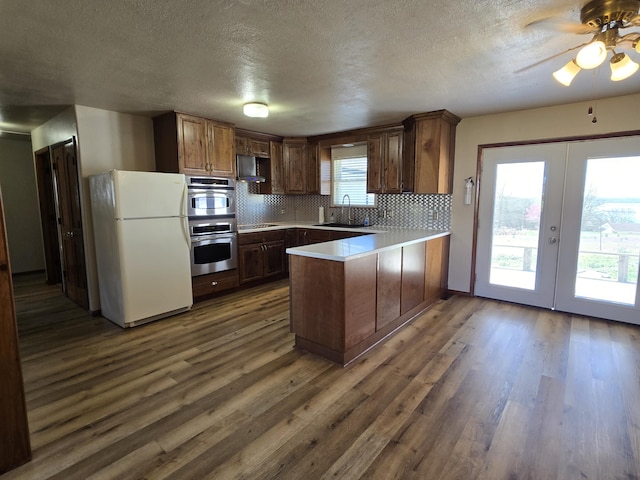 21282 County Road 295, Hermitage, MO 65668 - kitchen with a peninsula, black electric cooktop, a sink, dark wood finished floors, and freestanding refrigerator