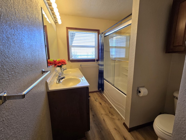 21282 County Road 295, Hermitage, MO 65668 - full bathroom with bath / shower combo with glass door, double vanity, toilet, wood finished floors, and a textured wall