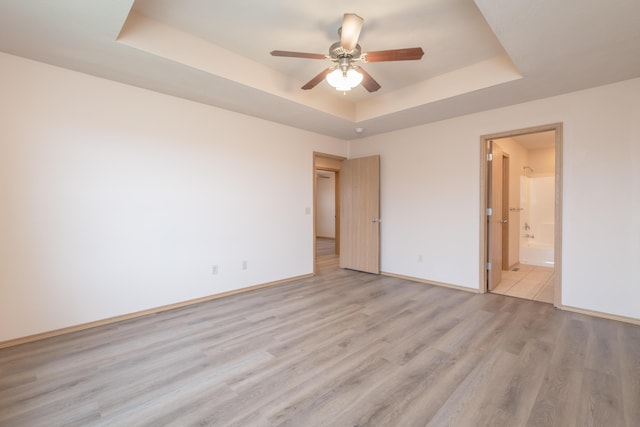 3335 W Countryside Dr, Springfield, MO 65807 - unfurnished bedroom featuring ensuite bathroom, baseboards, ceiling fan, a tray ceiling, and light wood finished floors