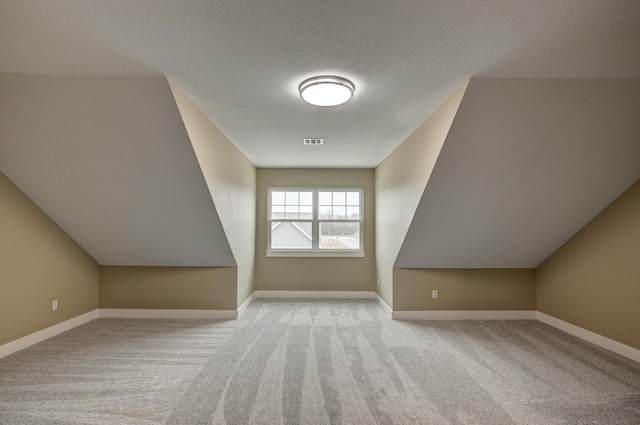 additional living space with baseboards, visible vents, and carpet floors