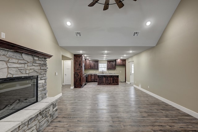 unfurnished living room featuring baseboards, a fireplace, visible vents, ceiling fan, and wood finished floors