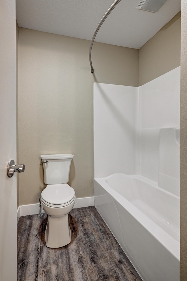 full bath featuring shower / bathing tub combination, visible vents, toilet, wood finished floors, and baseboards