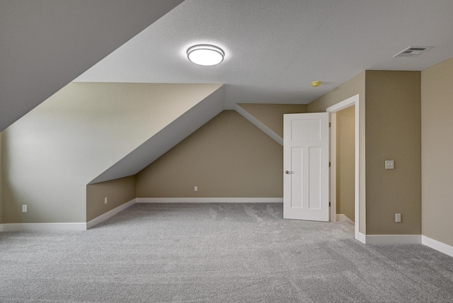 bonus room with a textured ceiling, visible vents, carpet floors, lofted ceiling, and baseboards