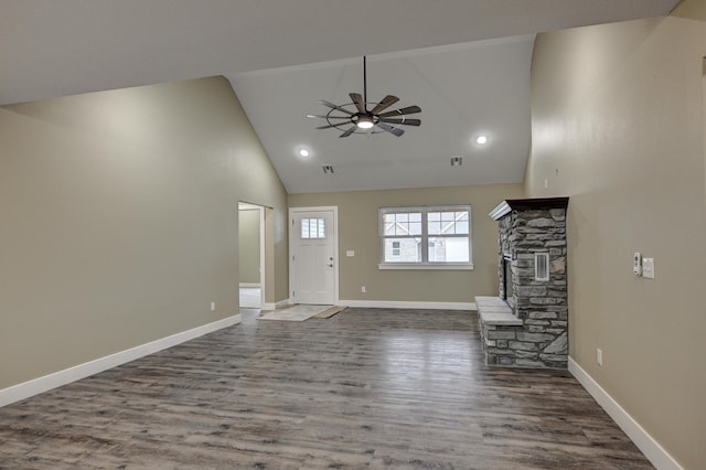 unfurnished living room featuring high vaulted ceiling, a ceiling fan, a stone fireplace, wood finished floors, and baseboards