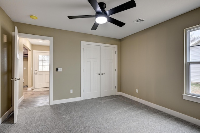 unfurnished bedroom featuring visible vents, baseboards, a closet, a ceiling fan, and carpet