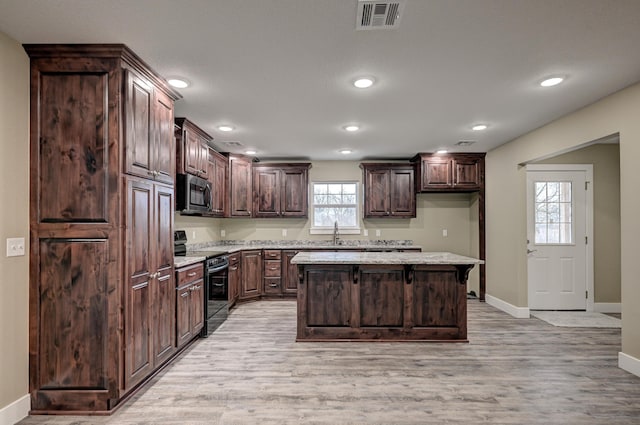 kitchen with visible vents, a center island, dark brown cabinets, stainless steel microwave, and electric range