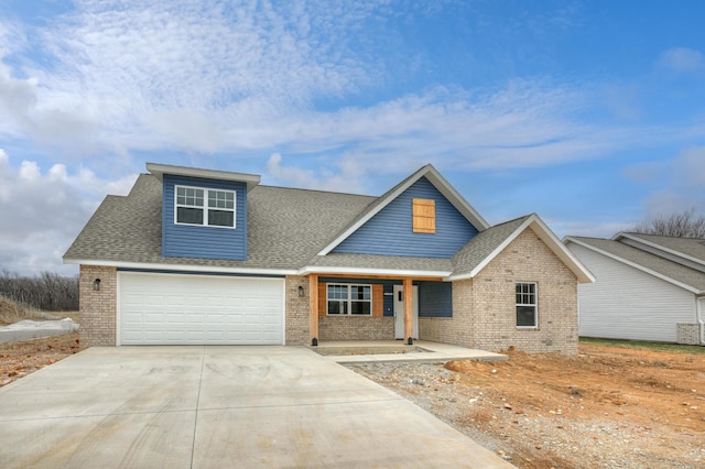 view of front facade with an attached garage, covered porch, concrete driveway, brick siding, and roof with shingles