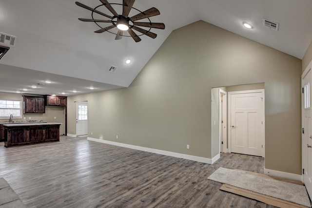 unfurnished living room with ceiling fan, a sink, visible vents, and plenty of natural light