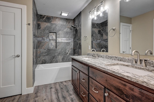 bathroom featuring a sink, double vanity, shower / bathing tub combination, and wood finished floors