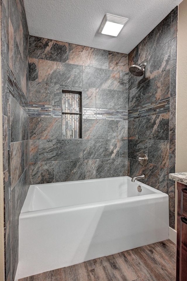 bathroom with a textured ceiling, wood finished floors, tub / shower combination, and vanity