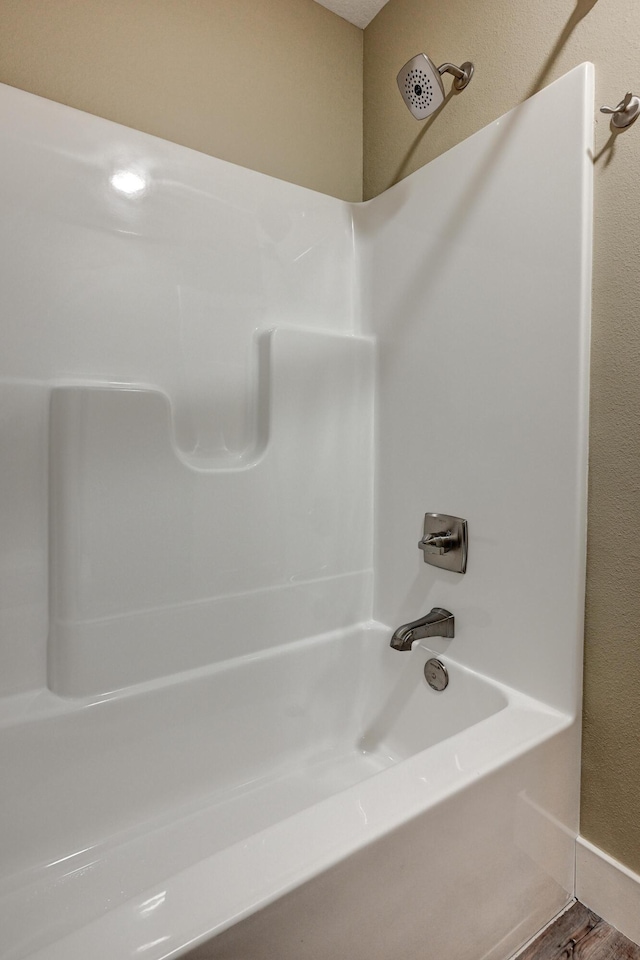 bathroom with a textured wall and shower / washtub combination