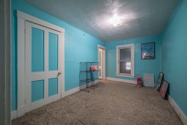 interior space with carpet floors, a textured wall, and a textured ceiling