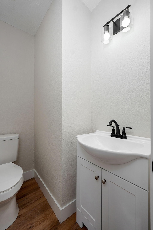 2558 W Village Ln, Springfield, MO 65807 - half bathroom featuring toilet, baseboards, vanity, and wood finished floors