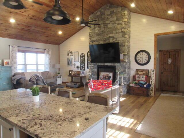 living area featuring light wood-style flooring, a fireplace, wooden ceiling, and high vaulted ceiling