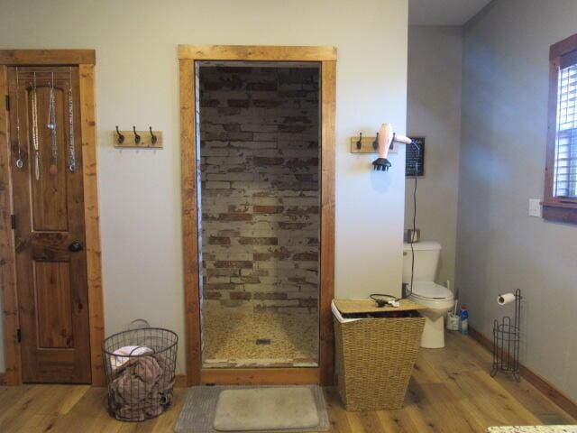 bathroom featuring baseboards, a stall shower, toilet, and wood finished floors