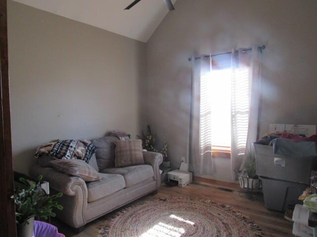 living room with ceiling fan, plenty of natural light, vaulted ceiling, and wood finished floors