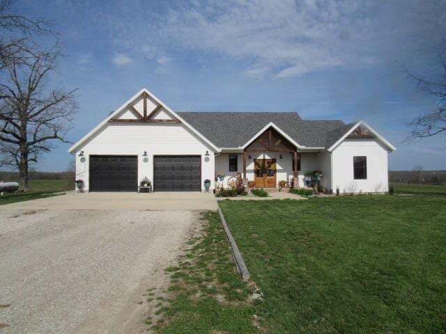 modern farmhouse featuring an attached garage, dirt driveway, and a front lawn