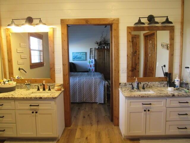 bathroom featuring vanity, ensuite bath, wood finished floors, and wooden walls
