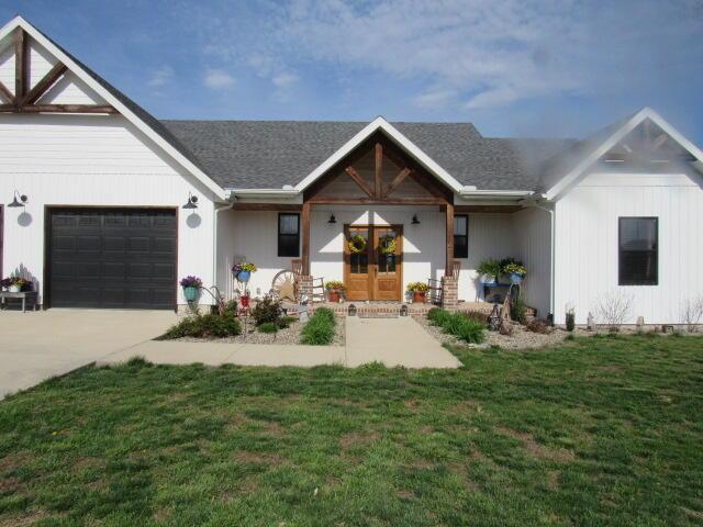 view of front of house featuring french doors, a garage, driveway, and a front yard