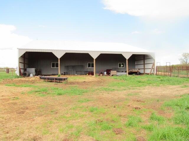 back of house featuring a pole building, fence, and an outbuilding